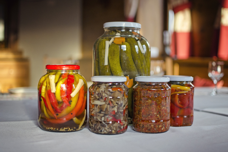 Glass jars filled with preserved vegetables arranged on a table in the restaurant