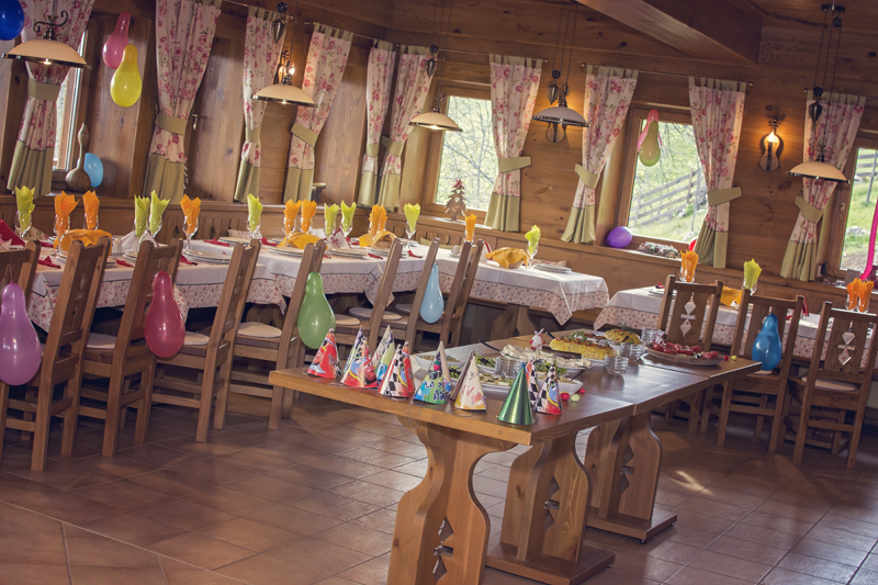 Long wooden dining tables set with plates, glasses, and colourful decorations